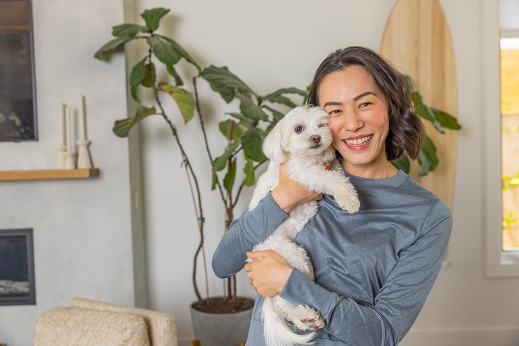 woman holding dog with tall planbt in background